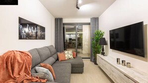 A modern living room with a grey sofa, a flat-screen TV, and a minimalist console table. - Beautiful, cozy APT just off the Promenade & WIFI (Tas-Sliema)
