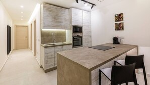 Une cuisine moderne dotée d’appareils électroménagers intégrés, d’un îlot central et d’un coin repas avec des chaises.
