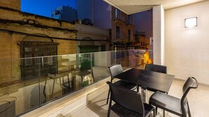 Un balcon doté d’une balustrade en verre, d’une table et de chaises.