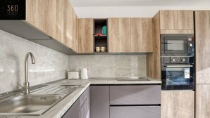 A modern kitchen with a stainless steel sink, a built-in oven, and wooden cabinets. - A beautiful, spacious penthouse (Il-Gżira)