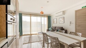 A modern apartment with a dining area, a sofa, and a large window. - A beautiful, spacious penthouse (Il-Gżira)