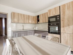 A modern kitchen with wooden cabinets, a built-in oven, and a dining area with a table and chairs.