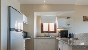Une cuisine moderne équipée d’un réfrigérateur, d’un four à micro-ondes, d’un évier et d’un lave-linge.