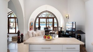 A spacious kitchen with a large island, a dining area with a view of the beach, and a TV.