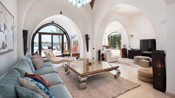 A spacious living room with a glass coffee table, a sofa, and a television.