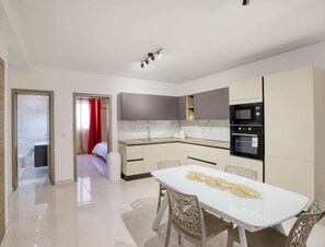 A modern kitchen with a dining area, a separate bedroom, and a bathroom. - Spacious, brand new 2BR, just off the promenade (Il-Gżira)