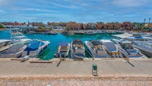 Un port de plaisance avec des bateaux amarrés, un ciel dégagé et des bâtiments en arrière-plan.