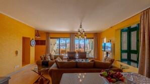 Un salon avec un canapé, une table basse et une vue sur la ville grâce à de grandes fenêtres.
