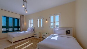 Une chambre avec deux lits, une fenêtre donnant sur un beau paysage, un lustre et un tapis à motifs.