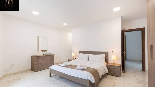 Ein modernes Schlafzimmer mit einem großen Bett, Nachttischen, einem Kleiderschrank und einem Spiegel.