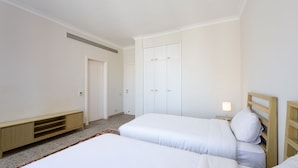 Ein Schlafzimmer mit zwei Betten, einem Kleiderschrank, einem Nachttisch mit Lampe und einem Teppichboden.