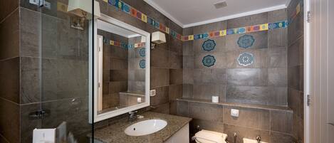 A modern bathroom with a granite countertop sink, a large mirror, a toilet, and a bidet.