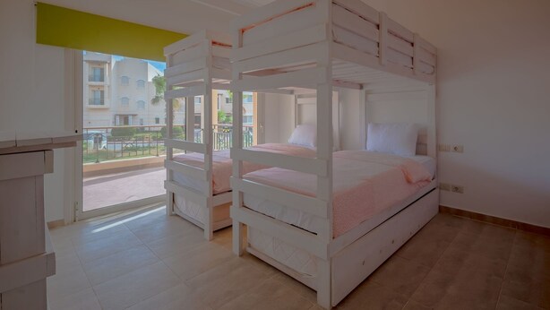 A hotel room with bunk beds, a balcony, and a view of the outside buildings. - VESTA - Luxury APT - 2BR - Golf (I) (Hurghada)