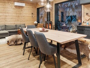 Un interior moderno con una mesa de comedor de madera, sillas tapizadas de gris, un sofá y una chimenea.