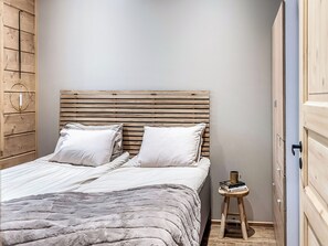 A bedroom with a wooden headboard, a bed with white bedding, a bedside table with a book and a mug, and a wooden wardrobe. - Villa huili by Interhome (Kuusamo)