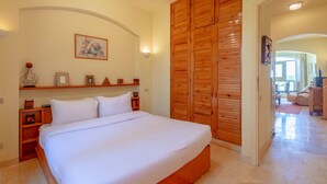 Een slaapkamer met een groot bed, een houten garderobe en een klein plankje met ingelijste foto's.