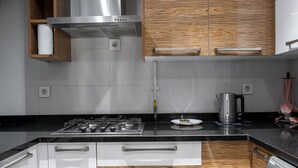 A modern kitchen with a gas stove, stainless steel appliances, wooden cabinetry, and a black countertop. - VESTA - Luxury apt - 2BR - CFC (II) (New Cairo City)