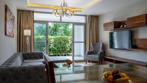 A modern living room with a sofa, armchair, and a glass-top dining table with fruit. - VESTA - Luxury apt - 2BR - CFC (II) (New Cairo City)