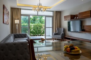 A modern living room with a sofa, armchair, and a glass-top dining table with fruit. - VESTA - Luxury apt - 2BR - CFC (II) (New Cairo City)