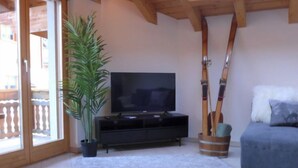 A living room with a TV, a plant, skis, and a sofa. - Arbgrat by Interhome (Täsch)