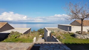 A coastal property with a stone pathway leading to two modern buildings, one with a sloped roof and the other with a flat roof, overlooking the sea. - Studio Cabine by Interhome (Saint-Florent)