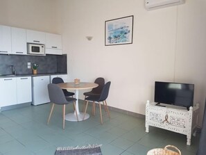 A modern kitchen with white cabinets, a microwave, and a dining area with a round table and chairs.