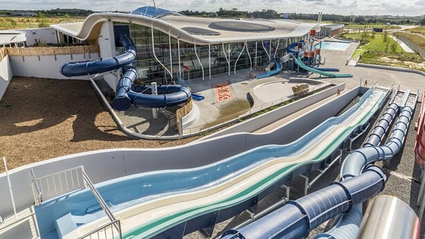 Een waterpark met glijbanen en een moderne gebouwstructuur.