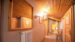 Un pasillo con paredes de madera, un radiador y un banco.
