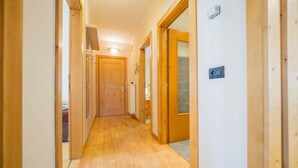 A narrow hallway with wooden flooring and doors leading to rooms. - You'll have everything at your fingertips by staying at Quadrilocale Aprica! (Livigno)