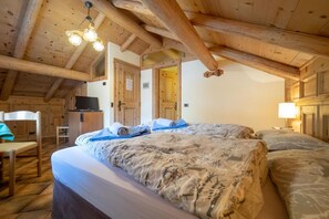 A cozy room with a wooden ceiling, two beds with patterned bedding, a desk, and a television. - Spacious accommodation for your next stay in Livigno (Livigno)