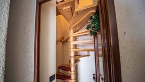 Eine hölzerne Wendeltreppe mit roten Stufen, die zu einer Zwischenebene führt.