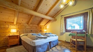 Ein gemütliches Schlafzimmer in einer Blockhütte mit einem großen Bett, Holzwänden und einem Fenster mit Vorhängen.