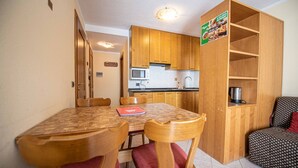 A compact kitchen with wooden cabinets, a microwave, and a coffee maker. - Residence Livigno is waiting for you to have an unforgettable experience! (Livigno)