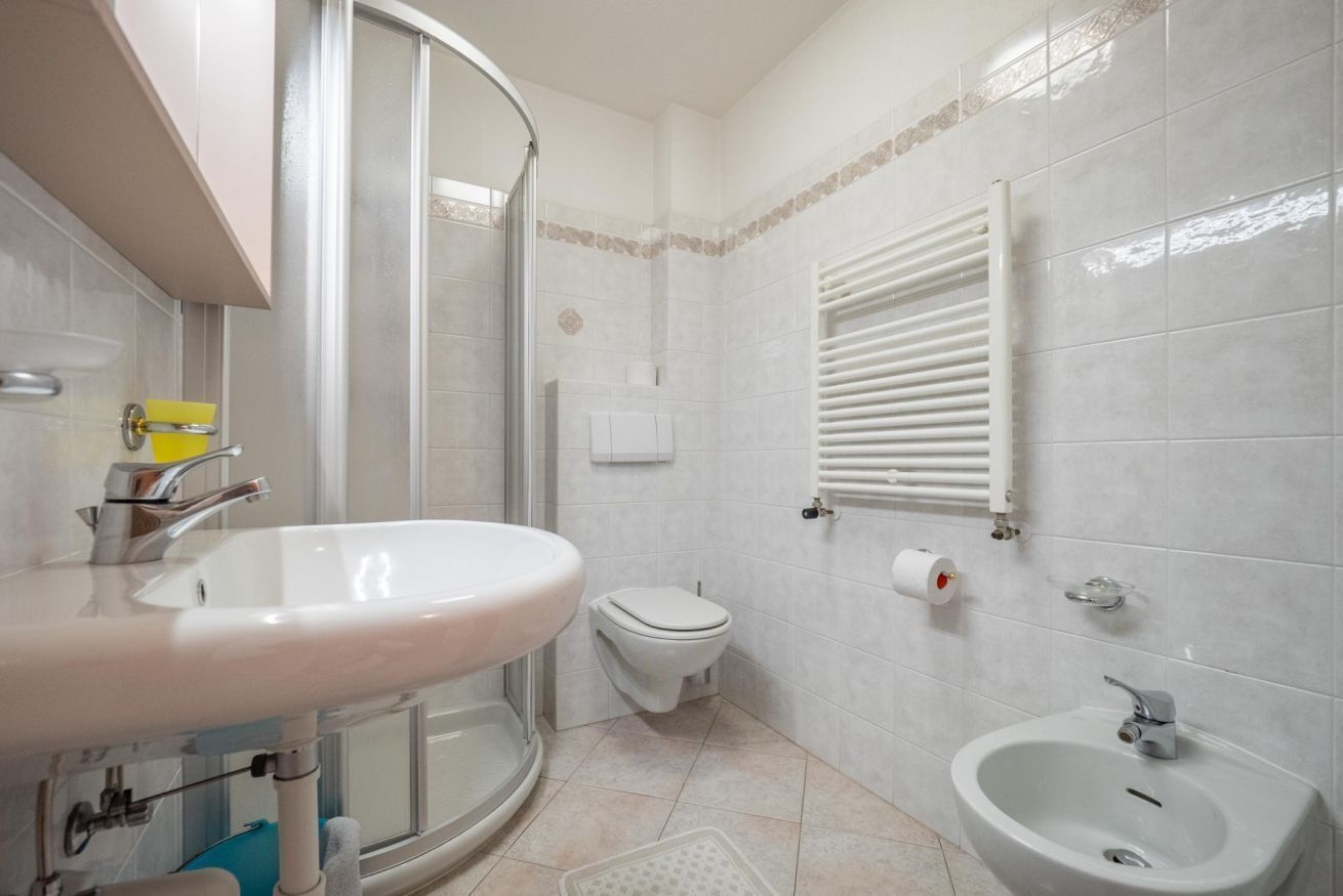 Een badkamer met wastafel, toilet, douche en toiletbrons.