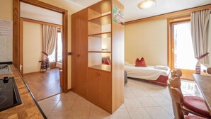 A room with a bed, a wooden wardrobe, a dining table with chairs, and a window with curtains. - Residence Livigno is waiting for you to have an unforgettable experience! (Livigno)