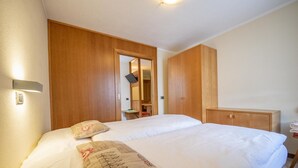 A hotel room with a large bed, wooden wardrobe, and a mirror. - Autonomy, but also comfort? Residence Livigno is the one for you! (Livigno)