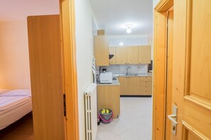 Eine kleine Küche mit Holzausstattung, einer Arbeitsplatte, einer Mikrowelle und einem Spülbecken.