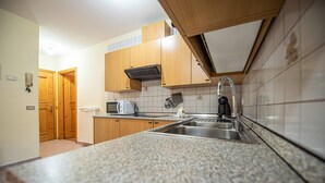 A kitchen with granite countertops, wooden cabinets, a stainless steel sink, and a microwave.