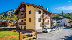 A multi-story building with balconies, a church, and a mountain backdrop.