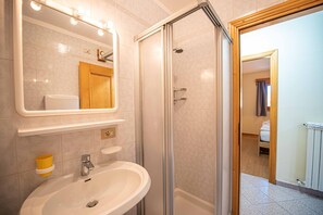 Ein Badezimmer mit einer Duschkabine, einem Waschbecken und einem beleuchteten Spiegel.