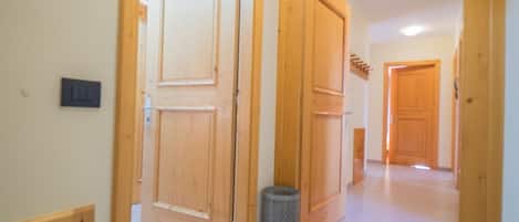 A hallway with wooden doors and a trash can.