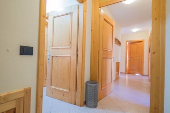 Un pasillo con puertas de madera y un cubo de basura.