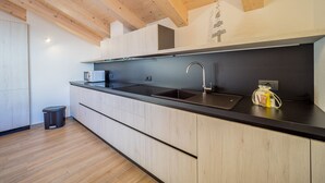 Una cocina moderna con vigas de madera, encimera negra y pileta de acero inoxidable.