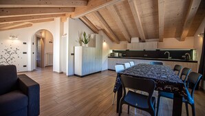 Una cocina moderna con vigas de madera, un comedor con mesa y sillas, y un pasillo con radiador.