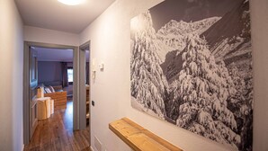 Ein Flur mit einer hölzernen Bank, einem Gemälde einer verschneiten Berglandschaft und einem Telefon an der Wand.