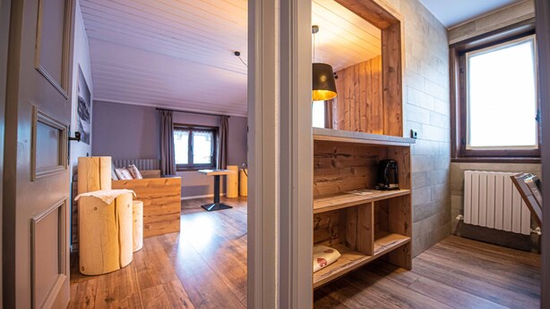 Ein gemütliches Zimmer mit Holzboden, einer eingebauten Bank, einem Couchtisch und einem Fenster mit Vorhängen.