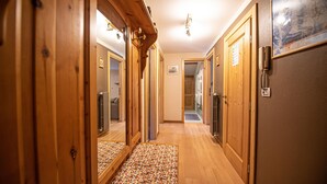 A hallway with wooden doors, a patterned rug, and a framed picture on the wall. - Your next stay in Livigno without giving up anything! (Livigno)