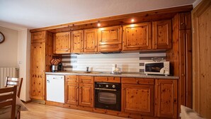 A kitchen with wooden cabinets, a dishwasher, an oven, and a microwave. - Your next stay in Livigno without giving up anything! (Livigno)