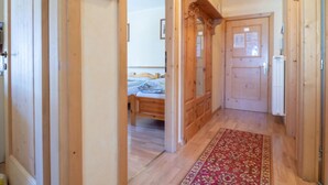 Ein Flur mit Holztüren, einem Bett im Hintergrund und einem roten, gemusterten Teppich.