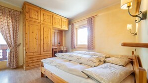 Ein Schlafzimmer mit einem hölzernen Bett, einem Kleiderschrank und einem Fenster mit Vorhängen.